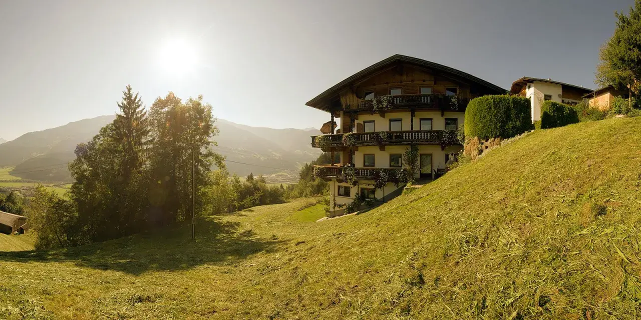 Sonnenbeschienene Alpenlandschaft mit einem traditionellen Haus, das an die Familie Schwarzenberg erinnert.