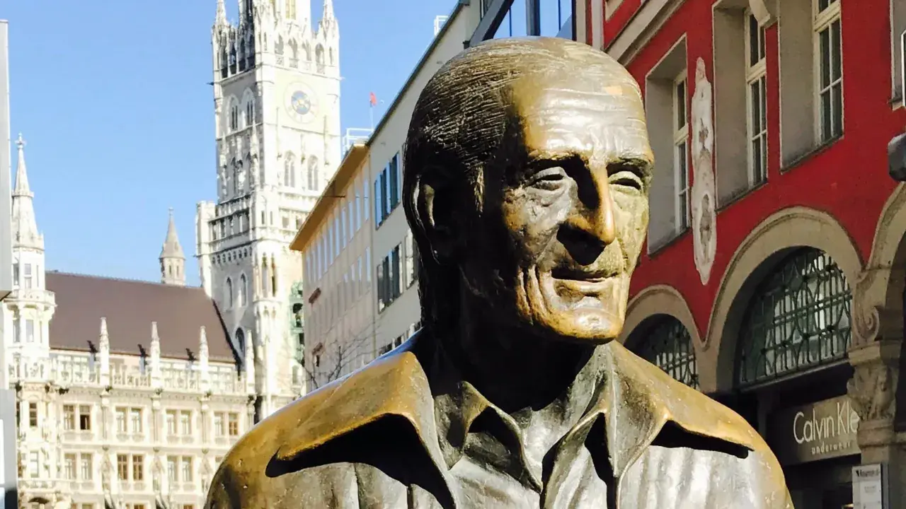 Bronzestatue von Sigi Sommer in München, mit dem Neuen Rathaus im Hintergrund.