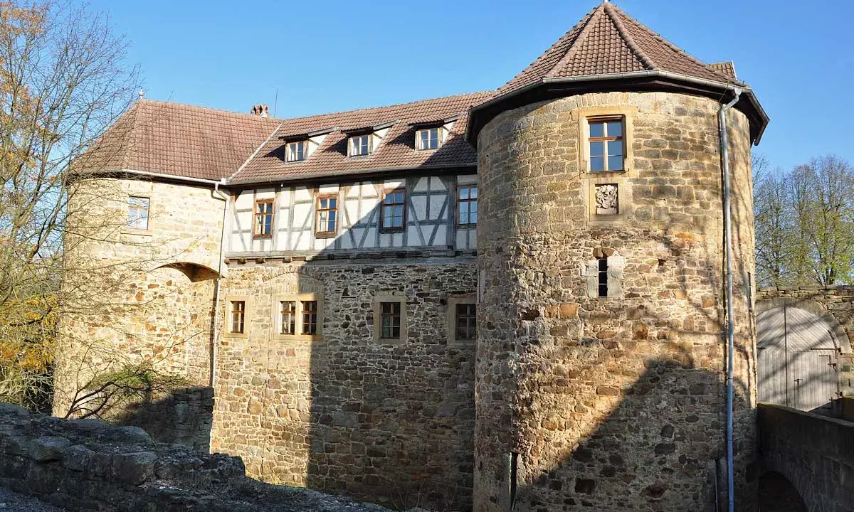 Die Burg von Bibra, ein historisches Gemäuer mit Rundturm und Fachwerk, strahlt im Sonnenlicht.