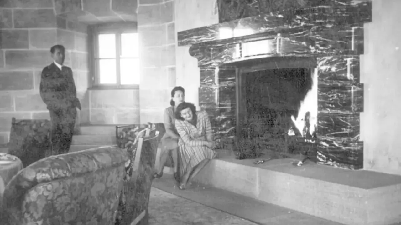 Zwei Frauen entspannen sich 1944 am Kamin im Kehlsteinhaus. Ein Mann steht im Hintergrund.