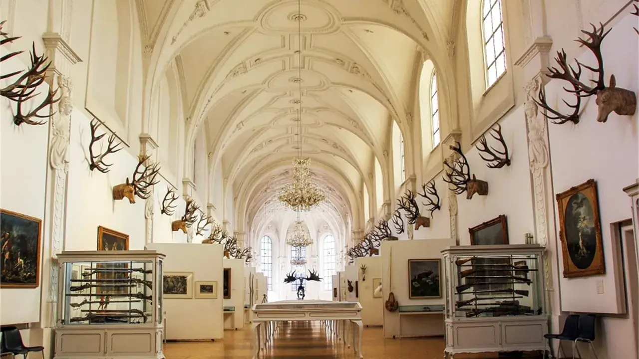Prunkvolle Halle des deutschen Jagd- und Fischereimuseums mit Geweihen, Waffen und Gemälden.