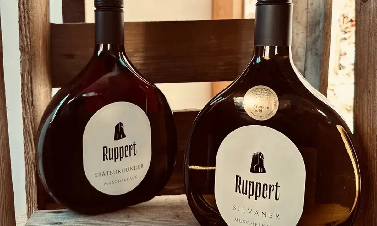 Zwei Flaschen Ruppert Wein, Spätburgunder und Silvaner, stehen in einer Holzkiste. Ein Zeichen für den Weinbau Franken.