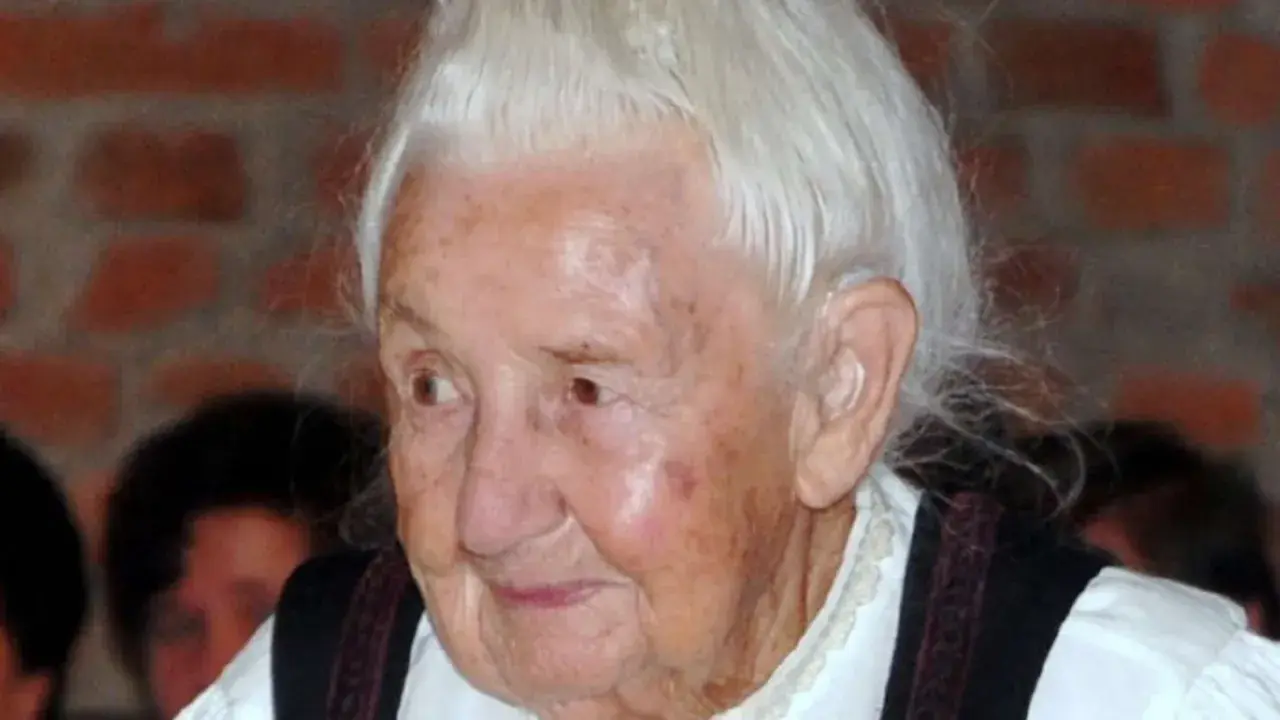Porträt einer älteren Frau mit weißem Haar und traditioneller Kleidung. Traudl Well lächelt sanft.