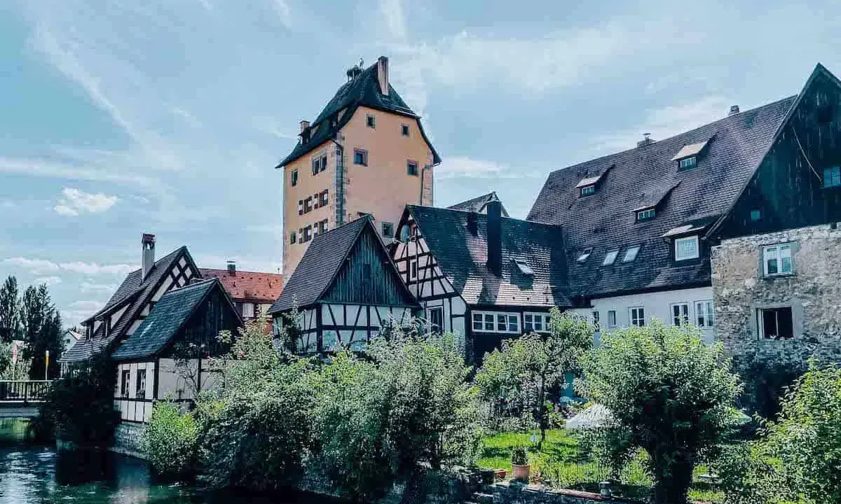 Fachwerkhäuser und ein hoher Turm am Flussufer in Hersbruck, Bayern.