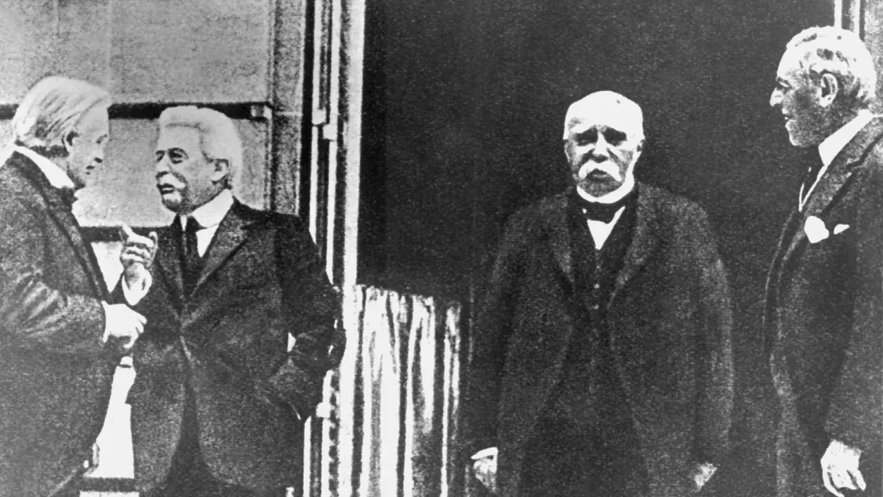 Vier Männer in Anzügen, die über den Friedensvertrag von Versailles diskutieren.