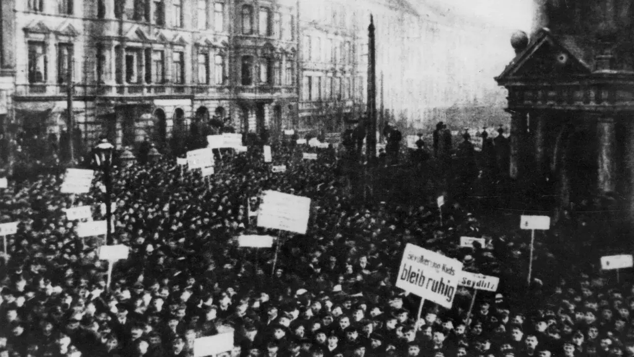 Massen demonstrieren in der Revolution 1918. Schilder mit Aufschriften wie "Seydlitz" und "Bleib ruhig" werden hochgehalten.