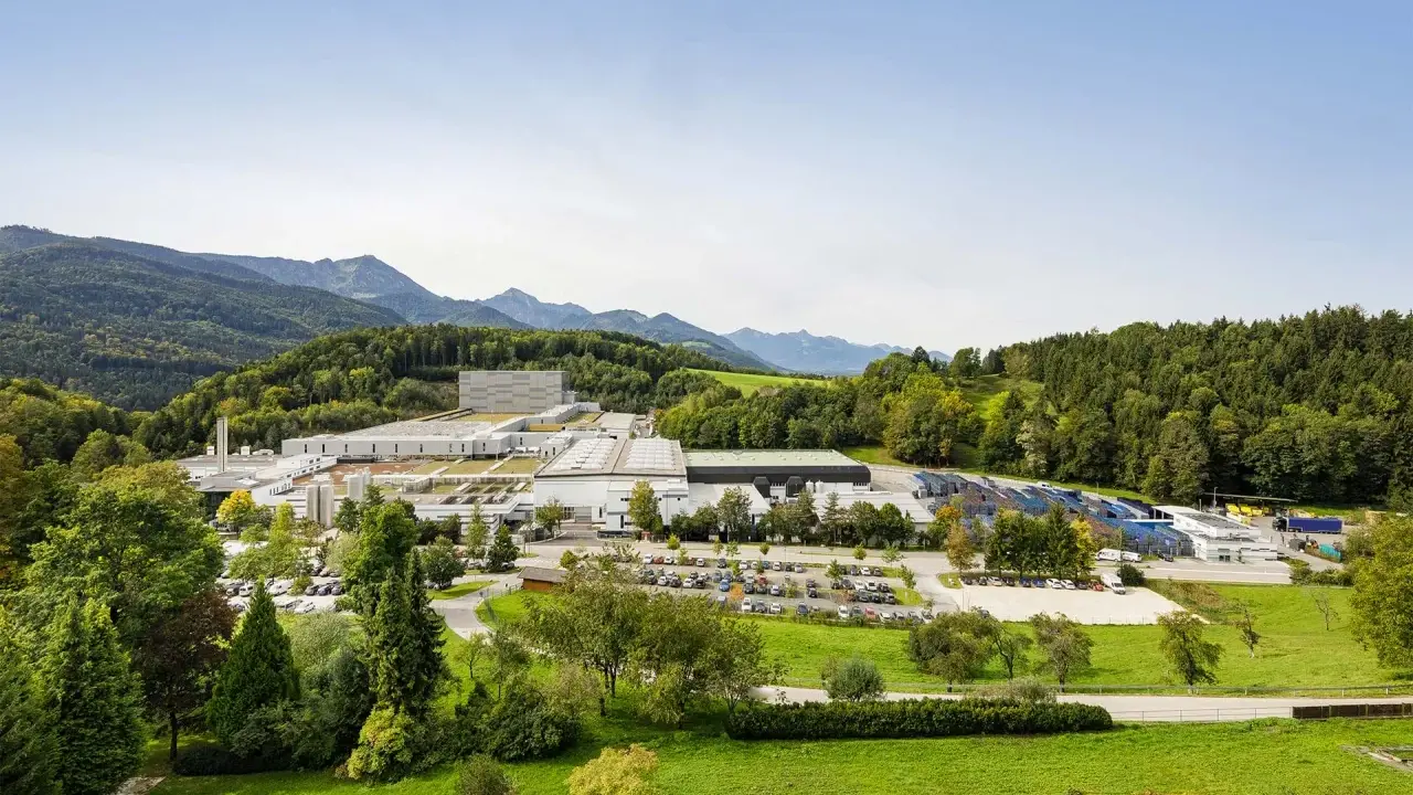 Großer Industriebetrieb in Bad Adelholzen, eingebettet in grüne Hügel und Berge.