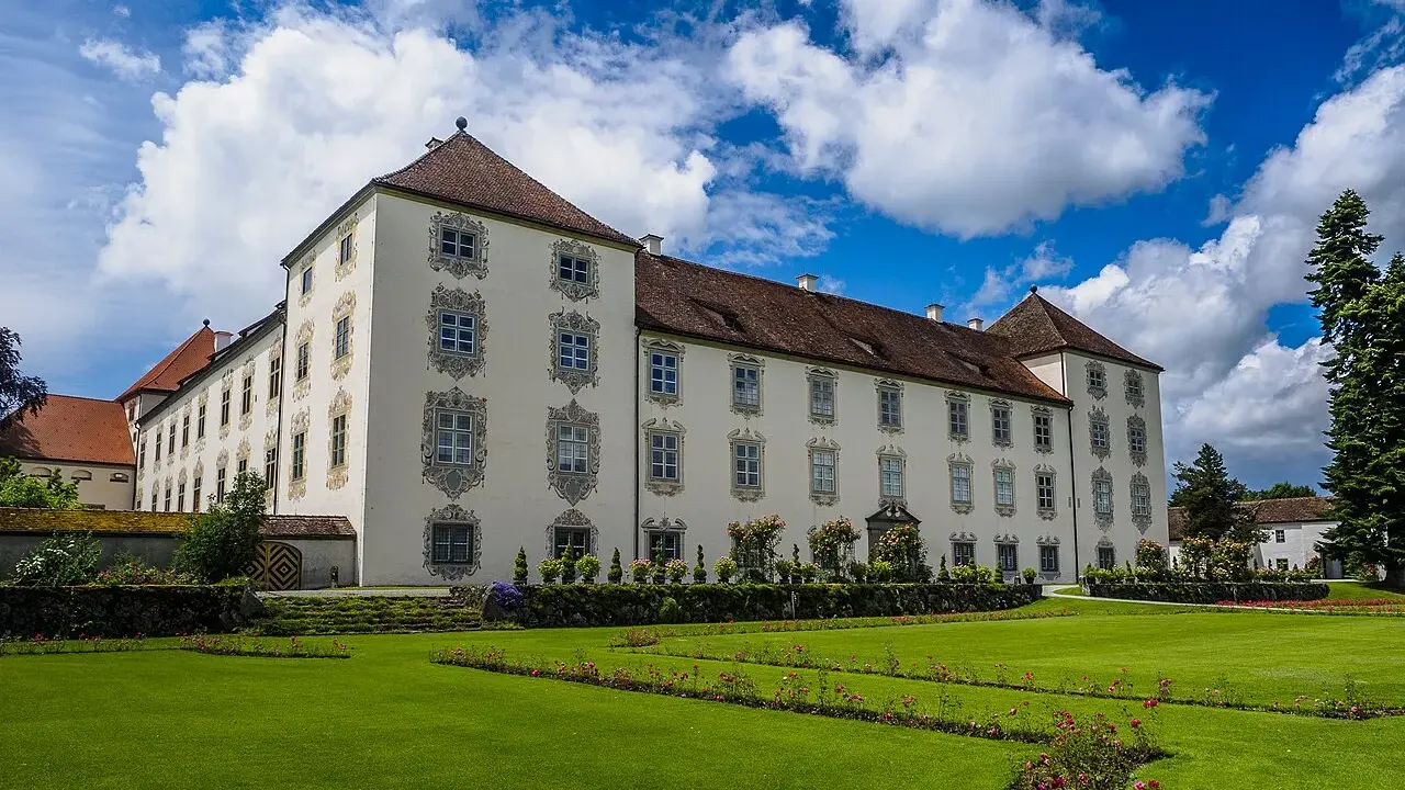 Schloss Waldburg-Zeil mit gepflegtem Garten und blauem Himmel mit Wolken.