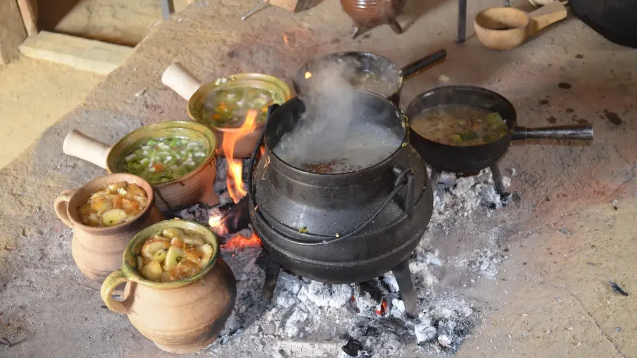 Ein mittelalterliches Festmahl: Eintöpfe und Suppen köcheln über offenem Feuer. Essen und trinken im Mittelalter war oft eine Gemeinschaftsangelegenheit.