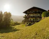 Sonnenbeschienene Alpenlandschaft mit einem traditionellen Haus, das an die Familie Schwarzenberg erinnert.