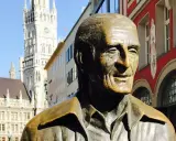 Bronzestatue von Sigi Sommer in München, mit dem Neuen Rathaus im Hintergrund.