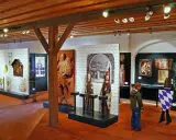 Museumsausstellung mit historischen Artefakten, darunter das Wittelsbacher Wappen, Skulpturen und Gemälde.