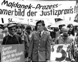 Demonstranten protestieren gegen das Majdanek-Urteil. Ein Mann in Uniform und ein Überlebender des Holocaust tragen Schilder, die gegen NS-Verbrechen und die Verjährung von Taten protestieren.