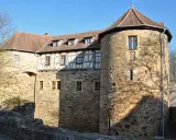 Die Burg von Bibra, ein historisches Gemäuer mit Rundturm und Fachwerk, strahlt im Sonnenlicht.