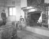 Zwei Frauen entspannen sich 1944 am Kamin im Kehlsteinhaus. Ein Mann steht im Hintergrund.