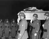 Militärische Ehreneskorte trägt einen mit Blumen geschmückten Sarg.