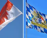 Zwei Fahnen im Wind: eine mit einem roten Ahornblatt, die andere mit dem Wappen des Freistaats Bayern, der stolz seine fränkischen Wurzeln zeigt.