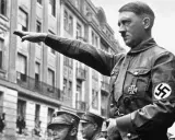 Adolf Hitler hebt den Arm zum Gruß. Seine Uniform zeigt das Hakenkreuz. Die Frage, wie kam Hitler an die Macht, beschäftigt Historiker bis heute.