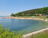 Sonniger Strandtag am Rothsee bei Heideck, Bayern. Menschen entspannen sich am Sandstrand, während Segelboote auf dem Wasser gleiten.