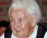 Porträt einer älteren Frau mit weißem Haar und traditioneller Kleidung. Traudl Well lächelt sanft.
