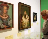 Eine Frau betrachtet Porträts der Familie Wittelsbach im Museum.
