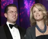 Ein Mann mit Brille und Fliege, Karl-Theodor zu Guttenberg, und eine Frau mit blonden Haaren und blauer Kette.