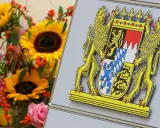 Das Staatswappen Bayerns, flankiert von Löwen, steht stolz neben einem bunten Blumenstrauß mit Sonnenblumen und Rosen.