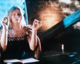 Annamirl Bierbichler in dunklem Kleid mit Pelzmantel, die Hände erhoben, im Schein einer Kerze.