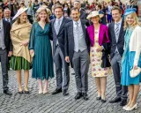 Gruppe von Personen in festlicher Kleidung, darunter Frauen in Kleidern und Männer in Anzügen.