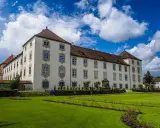 Schloss Waldburg-Zeil mit gepflegtem Garten und blauem Himmel mit Wolken.