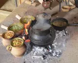 Ein mittelalterliches Festmahl: Eintöpfe und Suppen köcheln über offenem Feuer. Essen und trinken im Mittelalter war oft eine Gemeinschaftsangelegenheit.