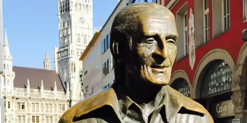 Bronzestatue von Sigi Sommer in München, mit dem Neuen Rathaus im Hintergrund.