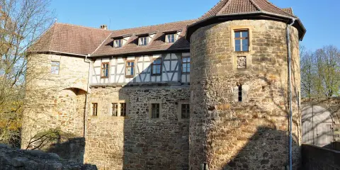 Die Burg von Bibra, ein historisches Gemäuer mit Rundturm und Fachwerk, strahlt im Sonnenlicht.