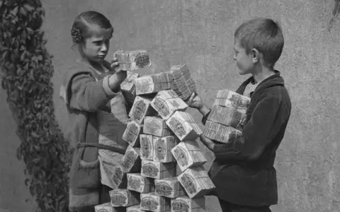 Kinder stapeln Bündel von Geldscheinen, ein Symbol für die Hyperinflation in Deutschland 1923.