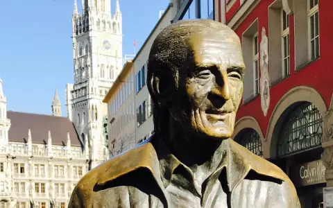 Bronzestatue von Sigi Sommer in München, mit dem Neuen Rathaus im Hintergrund.