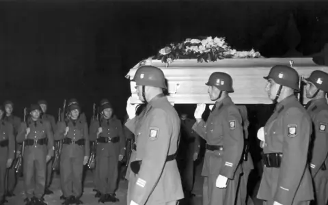 Militärische Ehreneskorte trägt einen mit Blumen geschmückten Sarg.