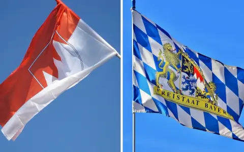 Zwei Fahnen im Wind: eine mit einem roten Ahornblatt, die andere mit dem Wappen des Freistaats Bayern, der stolz seine fränkischen Wurzeln zeigt.