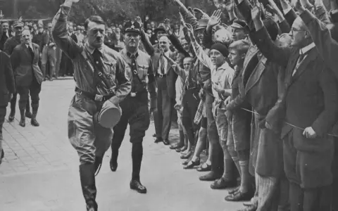 Adolf Hitler und Parteigenossen grüßen die Menge. Ein Bild, das den Aufstieg der NSDAP dokumentiert.