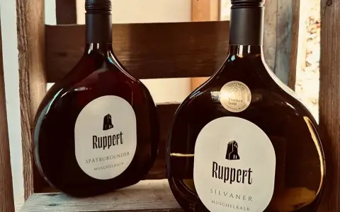 Zwei Flaschen Ruppert Wein, Spätburgunder und Silvaner, stehen in einer Holzkiste. Ein Zeichen für den Weinbau Franken.