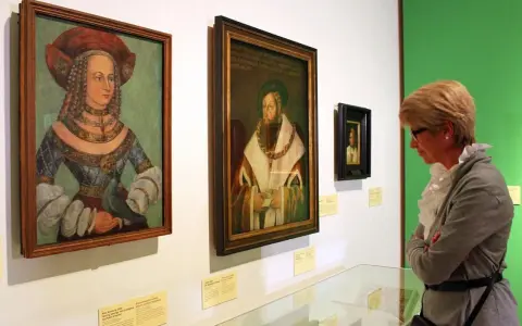 Eine Frau betrachtet Porträts der Familie Wittelsbach im Museum.