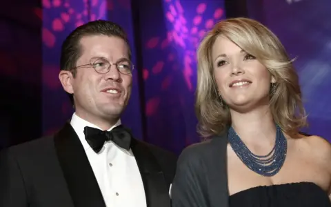 Ein Mann mit Brille und Fliege, Karl-Theodor zu Guttenberg, und eine Frau mit blonden Haaren und blauer Kette.