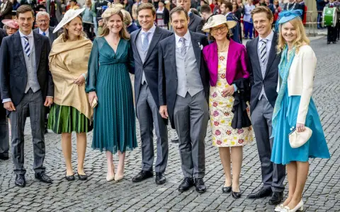 Gruppe von Personen in festlicher Kleidung, darunter Frauen in Kleidern und Männer in Anzügen.