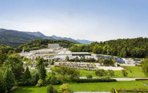 Großer Industriebetrieb in Bad Adelholzen, eingebettet in grüne Hügel und Berge.