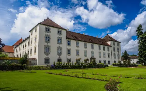Schloss Waldburg-Zeil mit gepflegtem Garten und blauem Himmel mit Wolken.