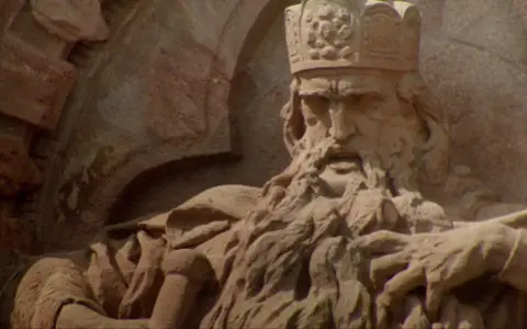 Steinskulptur von Friedrich I. Barbarossa mit Krone und Bart, der auf einem Thron sitzt.