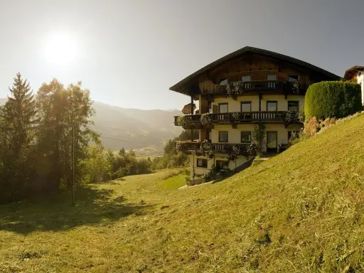 Sonnenbeschienene Alpenlandschaft mit einem traditionellen Haus, das an die Familie Schwarzenberg erinnert.