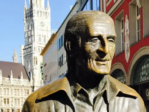 Bronzestatue von Sigi Sommer in München, mit dem Neuen Rathaus im Hintergrund.