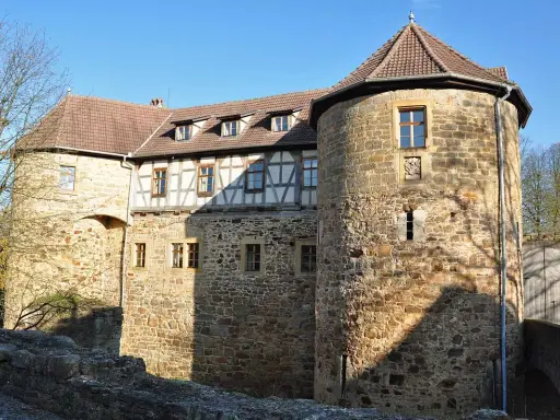 Die Burg von Bibra, ein historisches Gemäuer mit Rundturm und Fachwerk, strahlt im Sonnenlicht.