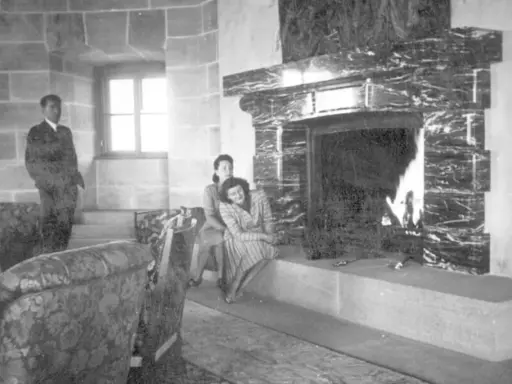 Zwei Frauen entspannen sich 1944 am Kamin im Kehlsteinhaus. Ein Mann steht im Hintergrund.