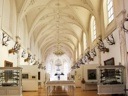 Prunkvolle Halle des deutschen Jagd- und Fischereimuseums mit Geweihen, Waffen und Gemälden.